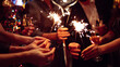 © maxbelchenko - A happy group is having fun at a bar, drinking drinks, and lighting sparklers in a cozy space. Young men and a woman are enjoying celebration and having fun at bar. Concept of party, celebration.