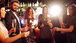 © maxbelchenko - A happy group is having fun at a bar, drinking drinks, and lighting sparklers in a cozy space. Young men and a woman are enjoying celebration and having fun at bar. Concept of party, celebration.