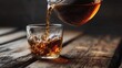 © mila103 - A person pours black tea from a glass pot into a clear cup resting on a wooden table. The warm drink creates ripples as it fills the cup during afternoon time.