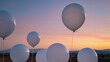 © Elenba - White balloons floating in soft airy neutral white tones against pastel sunset sky over landscape, dreamy serene celebration mood, high resolution stock photo