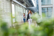 © Wavebreak Media - Female students walking campus walkway holding textbooks smartphone and red binder by potted shrubs