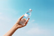 © Debi Kurnia Putra - Hand holding clear drinking water bottle under bright sky