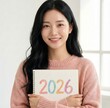 © small, slow, grow - Portrait of Happy Young Asian Woman Holding Sketchbook with Colorful 2026 New Year Drawing in Pink Sweater