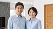 © Vasiliy - Happy middle aged Asian couple standing in a modern home interior. Portrait of a smiling Japanese husband and wife wearing matching blue shirts. Lifestyle concept
