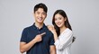 © Vasiliy - Happy young Asian couple standing together with man pointing finger at woman. Cheerful boyfriend and girlfriend portrait isolated on grey background. Recommendation concept