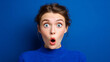 © Alive - Woman shows surprise against a blue background during daytime