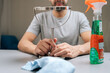 © dikushin - Cropped shot of man holding small magnifying cosmetic mirror, getting ready to clean reflecting surface with spray bottle of cleaner and blue microfiber cloth, performing household chores.