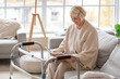 © Pixel-Shot - Senior woman with walker reading book on sofa at home