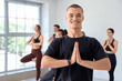 © Pixel-Shot - Sporty young man practicing yoga with group at gym