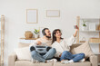 © Pixel-Shot - Young couple in headphones with boombox taking selfie on sofa at home