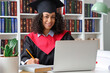 © Pixel-Shot - Pretty African-American female graduate with laptop sitting at table in library