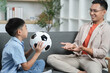 © itchaznong - Father and son enjoying soccer, sharing excitement at home