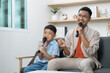 © itchaznong - Father and son singing together with microphones at home