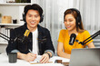 © InfiniteFlow - Smiling radio influencer hosts wearing headphones with channel social media online live streaming with talking topic on script note and laptop to listeners at morning time at studio record. Infobahn.