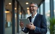 © si - Happy middle aged business man ceo wearing suit standing in office using digital tablet. He rejoices at the good news from the stock exchange. High quality