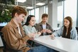© Serhii - Group of young adults playing cards in modern office during break time