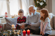 © Halfpoint - Small children with senior grandfather indoors at home at Christmas, looking at photographs.