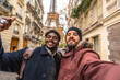 © unai - Two happy diverse men taking selfie in paris