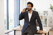 © sofiko14 - An Indian businessman wearing glasses is talking on the phone in his office, looking concerned