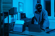 © New Africa - Thief in mask stealing laptop in office at night