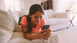 © Monkey Business - Young Girl Lying On Sofa In Lounge At Home Checking Social Media On Mobile Phone
