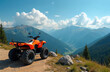 © miss irine - Orange all-terrain vehicle sits on a dirt path overlooking a deep mountain valley with dense green forests and distant blue peaks. The sky above is bright blue with scattered white clouds.