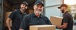 © miss irine - Team of movers in uniform unload boxes from truck. Happy man carries package. Professionals work together, delivering items safely. Moving company staff load cargo.