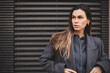 © zvkate - Close up portrait serious female with long hair in stylish grey wool coat and sweater looking at camera while standing on street with buildings in city. She look confidence.