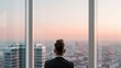© Kassiopeia  - A man looks out through a large office window. The scene shows a city skyline at sunset. The sky displays bright colors. The man stands still and observes the view