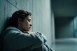 © Alona - Close-up of a young, distressed woman sitting against a cold concrete wall in a corridor, symbolizing mental anguish, existential loneliness, and emotional shutdown.