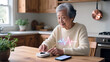 © LIDIIA - Elderly woman monitors heart health with smart device and digital ECG graphic.