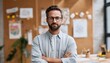© Andrii - Professional Hispanic Man In Beard And Glasses Standing In Modern Office, Crossing Arms, Surrounded By Cork Board And Supplies.