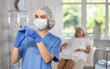 © JackF - Portrait of young nurse wearing blue medical scrubs, facial mask and disposable gloves with syringe in her hands
