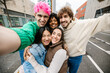 © Xavier Lorenzo - Group of young friends taking selfie on city street. Students enjoying playful moment together outdoors. Youth lifestyle and friendship concept.