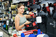 © JackF - Woman chooses and buys paint spray gun in a hardware store