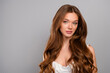 © Beauty Hero - Elegant portrait of a young woman with beautiful long brown hair and wavy hairstyle against a gray background
