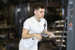 © JackF - Focused young guy in white sportswear training arms on cable machine at gym, performing triceps pushdowns as part of workout routine