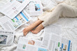 © Pixel-Shot - Legs of woman with newspapers on bed, top view