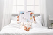 © Pixel-Shot - Young woman with newspaper lying in bedroom