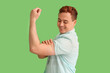 © Pixel-Shot - Young man showing arm with applied medical patch showing strength symbol on green background. Vaccination concept