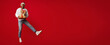 © Prostock-studio - A man wearing a Santa hat joyfully jumps in the air while holding wrapped gifts. The vibrant red background enhances the festive mood. It's a lively celebration of the holiday spirit.