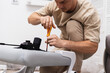 © Aboltin - Man carefully assembles chair, tightening screws and adjusting parts on floor. Scene captures focused moment of practical home work, surrounded by tools, details, and step-by-step effort.