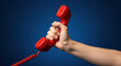 © abu - Hand Holding Bright Red Retro Style Telephone Handset Against Dark Blue Background