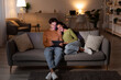 © Prostock-studio - Young couple sits comfortably on their sofa in the evening, exploring the internet on a tablet.