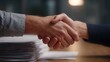 © Thares2020 - Business professionals shaking hands over a stack of documents