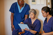 © Daniel2000/peopleimages.com - Conversation, meeting and tablet with medical team in hospital hallway for consulting or strategy. App, doctor and nurses with people in corridor of clinic for coaching, discussion or healthcare