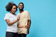 © SHOTPRIME STUDIO - Young Black couple dancing playfully against a vibrant blue background, showcasing joy and connection, perfect for lifestyle and relationship themes