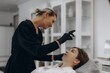 © Roman - Cosmetologist performing eyebrow threading procedure for client