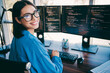 © deagreez - Female programmer at three monitors smiling while coding in modern office setting