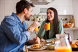© Impact Photography - Couple drinking fresh orange juice while having breakfast at home